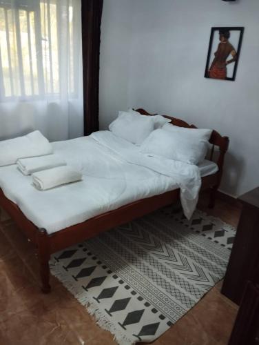 a bedroom with a bed with white sheets and pillows at Precious Homestays in Maragoli