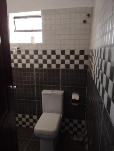 a bathroom with a toilet and black and white tiles at Precious Homestays in Maragoli