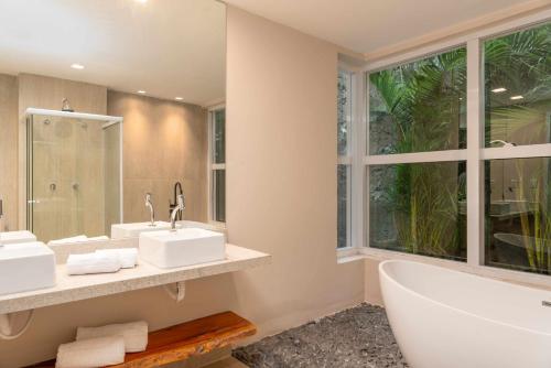 a bathroom with two sinks and a tub and a window at Transamerica Dunas de Marapé in Jequia da Praia