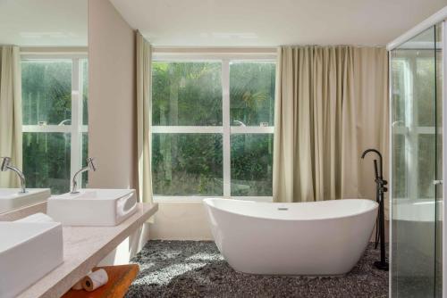 a white bathroom with two sinks and a large window at Transamerica Dunas de Marapé in Jequia da Praia