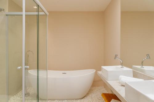 a bathroom with a tub and a glass shower at Transamerica Dunas de Marapé in Jequia da Praia