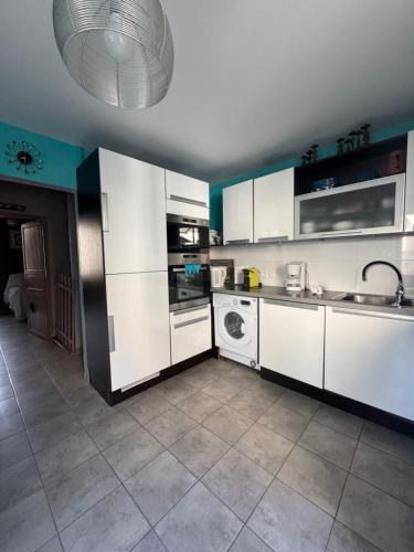une cuisine avec des armoires blanches et une laveuse et une sécheuse dans l'établissement La belle Callade, à Peyriac-de-Mer