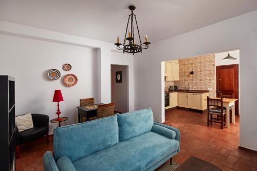 a living room with a blue couch and a kitchen at Monte do Forno in Vila Nova De Cacela