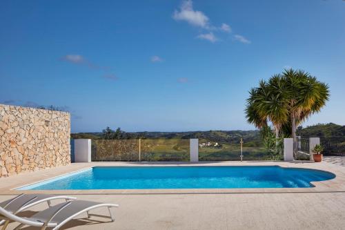 a swimming pool with two chairs and a palm tree at Monte do Forno in Vila Nova De Cacela
