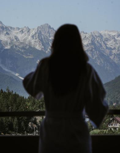 a person looking out of a window at mountains at Valbona Resort & Spa in Valbonë