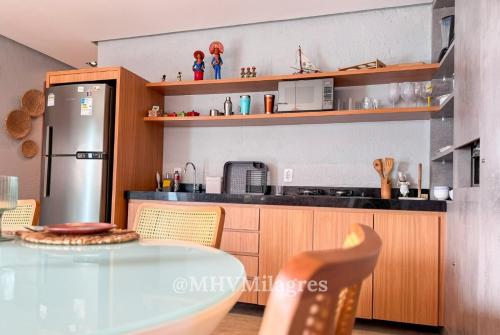 una cucina con tavolo e frigorifero di MHV Milagres - Lanaí 30 Refúgio próximo a Praia a poucos metros da Praia e da Capela dos Milagres a São Miguel dos Milagres