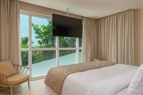 a bedroom with a bed and a large window at Transamerica Dunas de Marapé in Jequia da Praia