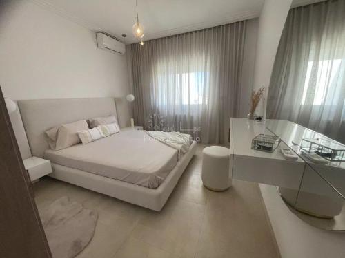 a white bedroom with a bed and a desk at Seasonal Rental S2 at Folla Palm Lake Monastir in Monastir
