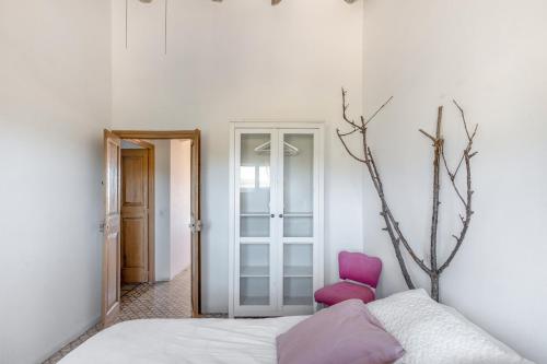 a bedroom with a bed and a pink chair at Cal Cabrer in Sant Jaume dels Domenys