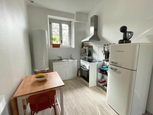 Il comprend une cuisine équipée d'un réfrigérateur blanc et d'une table en bois. dans l'établissement Appartement - Spacieux entre ville et nature !, à Lourdes
