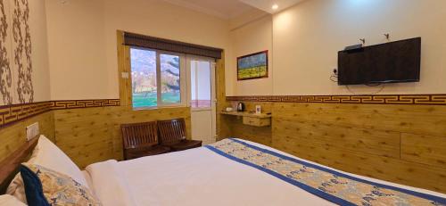ein Schlafzimmer mit einem Bett und einem Flachbildfernseher in der Unterkunft Hotel Samdupling Himalayan Brothers in Dharamshala