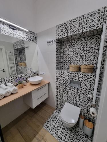 ein Bad mit einer schwarz-weiß gemusterten Wand in der Unterkunft Biały Kruk Apartamenty vis-a-vis Jasnej Góry 2a in Częstochowa