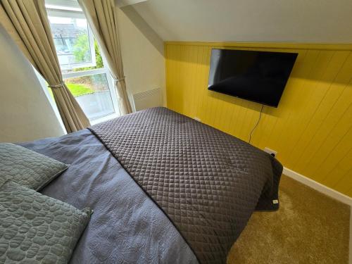 a bedroom with a bed and a tv on the wall at Gower Fresh Christmas Trees in Penclawdd