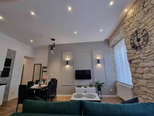 ein Wohnzimmer mit einem Sofa und einem Fernseher an der Wand in der Unterkunft Biały Kruk Apartamenty vis-a-vis Jasnej Góry 2a in Częstochowa