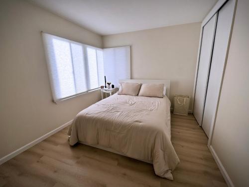 a white bedroom with a bed and a window at gateway to the ocean in Hawthorne