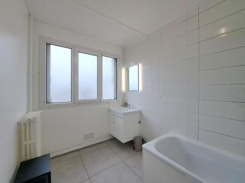 une salle de bain blanche avec une baignoire et un lavabo dans l'établissement Sofia - Grand appartement, à Reims
