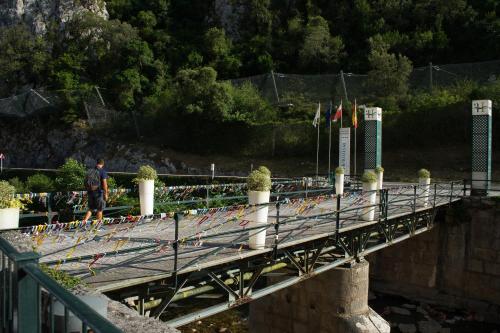 a man walking across a bridge with flags on it at Hotel Balneario La Hermida in La Hermida