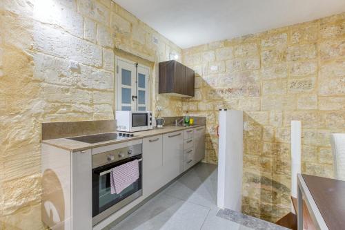 a kitchen with a stove and a microwave at Cosy 1BR home in the heart of vibrant Valletta by 360 Estates in Valletta