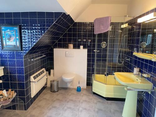 a blue tiled bathroom with a sink and a toilet at Villa Fracasso in Bad Salzuflen