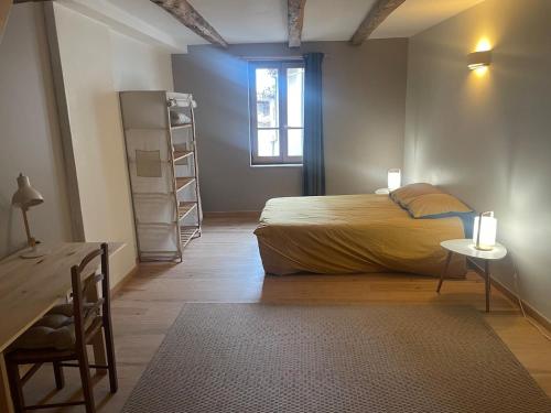 ヴィルフランシュ・ド・ルエルグにあるMaison typique dans la Bastide médiévaleのベッドと机と窓のある寝室