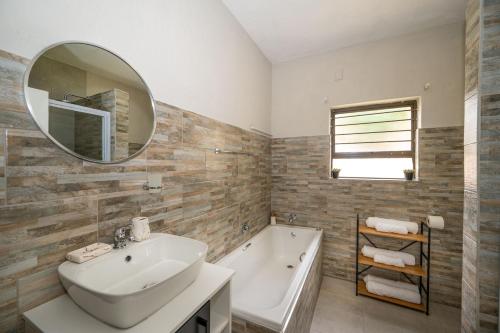 łazienka z umywalką, wanną i lustrem w obiekcie Self checkin - Modern 2 Bedroom Retreat - 103 w mieście Nelspruit