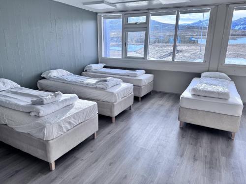 a room with four beds and windows in it at Hunavellir Guesthouse in Blönduós