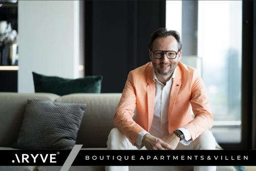 a man in an orange suit sitting on a couch at ARYVE Boutique-Apartments in bester Lage in Bad Hersfeld in Bad Hersfeld
