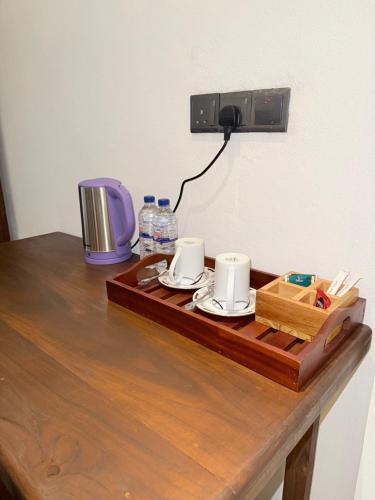 a wooden table with two cups and a camera on it at Devon Surf Inn Arugambay in Arugam Bay