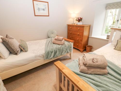 een slaapkamer met twee bedden, een ladekast en een raam bij River Dance Cottage in Leyburn