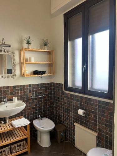 a bathroom with a sink and a toilet and a window at PortAtenea - Atenea Collection in Agrigento
