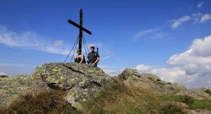 two people sitting on a rock next to a cross at Forellenwirt Bacher in Kirchberg