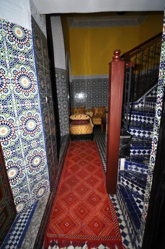 a staircase with a red carpet and blue and white tiles at Riad Khouloud in Fès
