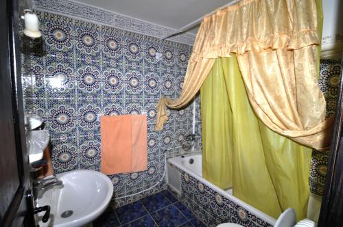 a bathroom with a shower curtain and a sink at Riad Khouloud in Fès