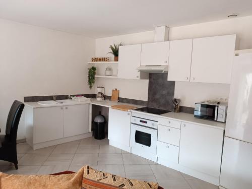 une cuisine blanche avec des armoires et des appareils blancs dans l'établissement Appartement Molini, à Porticcio