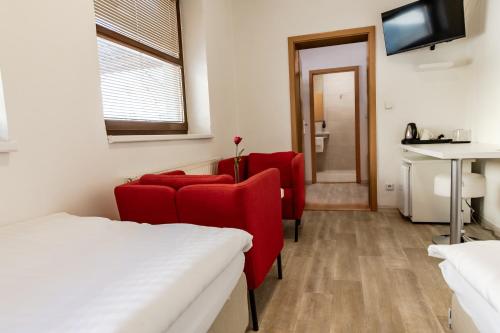 a room with red chairs and a table and a tv at Penzion Dena in Jihlava