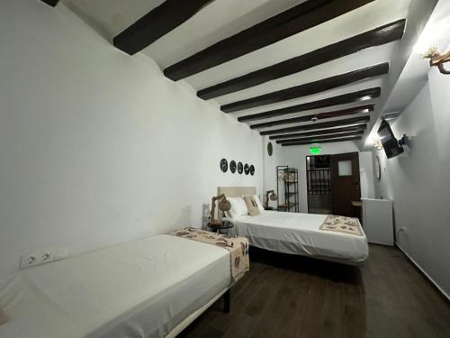 two beds in a room with white walls and wooden floors at Vilador Barcelona Beach Hotel in Masnou
