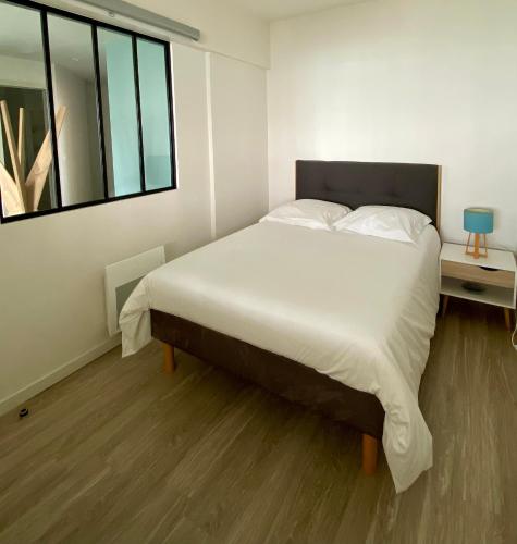 une chambre avec un grand lit blanc avec une fenêtre dans l'établissement Grand appartement vue mer panoramique, à Étretat