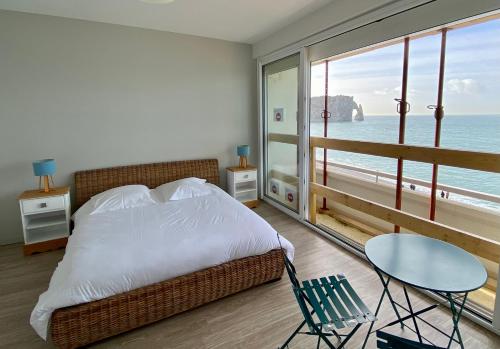 - une chambre avec un lit et une table et une vue sur l'océan dans l'établissement Grand appartement vue mer panoramique, à Étretat