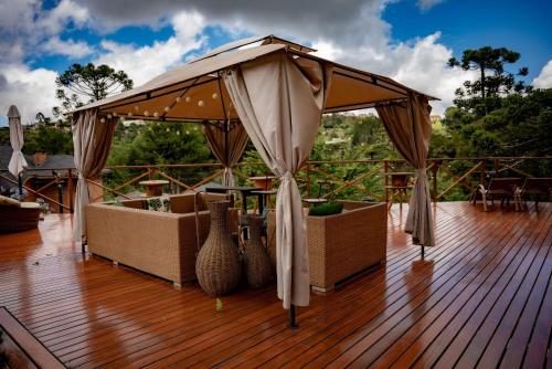 a canopy on a deck with chairs and tables at Pousada Chales da Mantiqueira - Campos do Jordão in Campos do Jordão