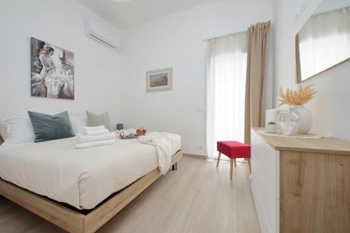 a white bedroom with a bed and a red chair at Elegante e Comodo - A pochi minuti dall'Aeroporto in Fiumicino