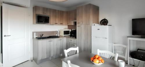 - une cuisine avec une table et un bol d'oranges dans l'établissement Appartement confortable à Remoulins, 49 m² avec piscine, à Remoulins