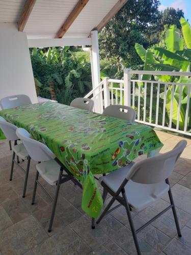 una mesa con sillas y un mantel verde en el patio en Le Paradis, en Capesterre-Belle-Eau