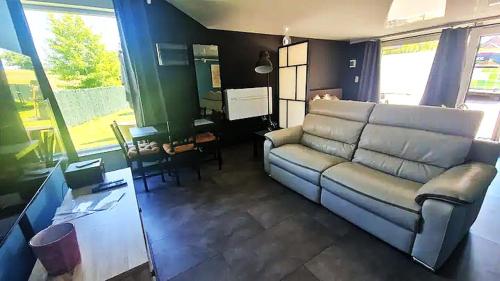 a living room with a couch and a piano at Au Petit Seny, gîte charme et nature avec jacuzzi pro in Tinlot