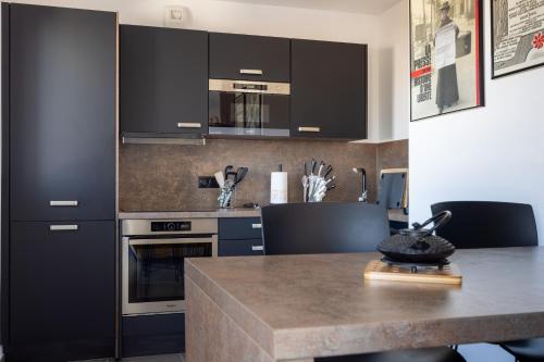 une cuisine avec des armoires noires et un comptoir dans l'établissement Atelier Edonya - Au coeur de la Teste, à La Teste-de-Buch