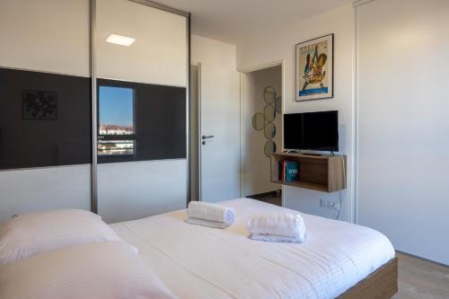 a bedroom with a large white bed and a tv at Atelier Edonya - Au coeur de la Teste in La Teste-de-Buch
