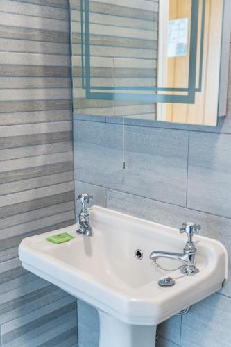 a bathroom with a white sink and a mirror at Rooms at The Highcliffe in Aberporth
