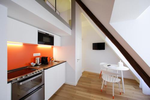 a kitchen with orange and white walls and a table at Les Maisons du Pont - Charme & Caractère in Aubusson
