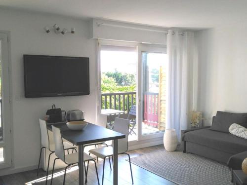 un salon avec une table et une télévision murale dans l'établissement Ambiance Cosy Capbreton, à Capbreton