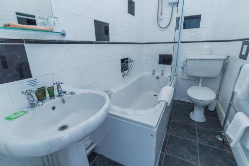 a white bathroom with a sink and a toilet at Rooms at The Highcliffe in Aberporth