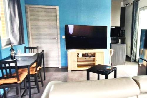 a living room with a flat screen tv and a table at Au Petit Seny, gîte charme et nature avec jacuzzi pro in Tinlot